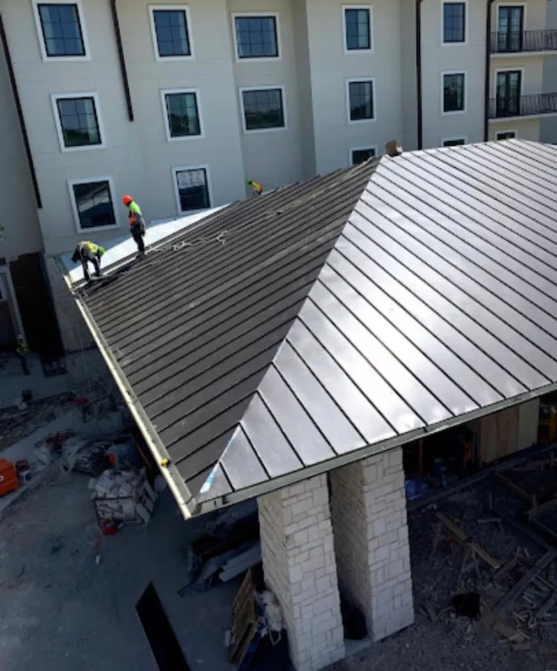 Crew installing standing seam metal roof panels on a commercial project in Norwood